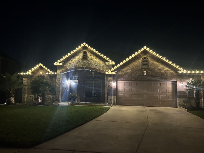 C9 Christmas lights installed along the rooflines of a brick and stone home in San Antonio