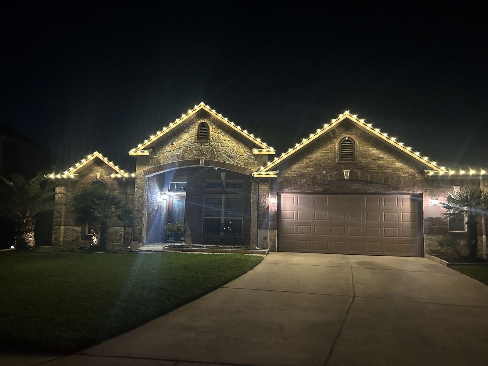 C9 Christmas lights installed along the rooflines of a brick and stone home in San Antonio