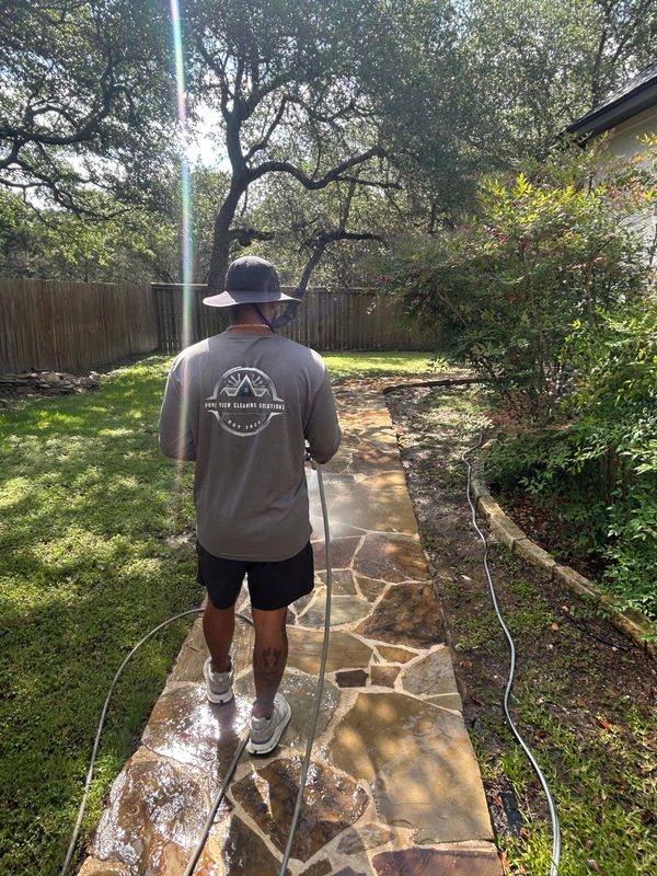 Pure View crew member pressure washing a flagstone walkway at a San Antonio home