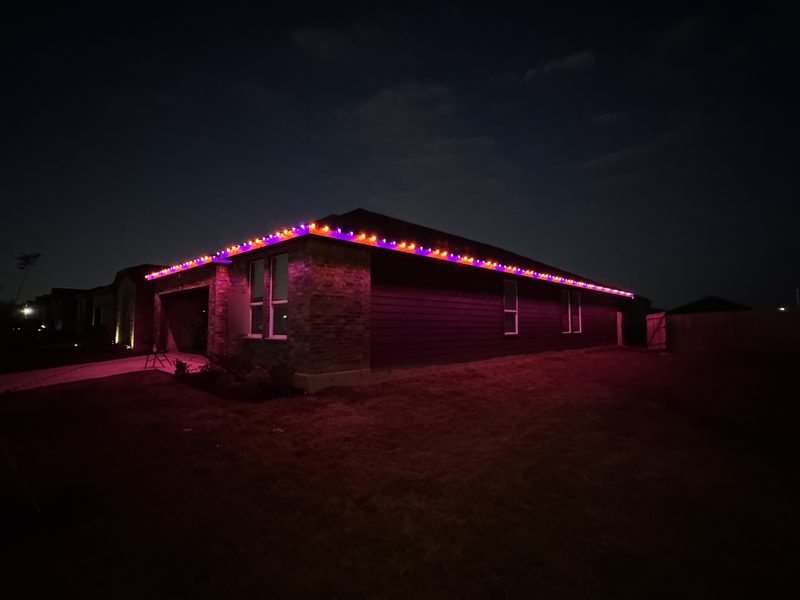 Orange and purple C9 lights along a home's roofline