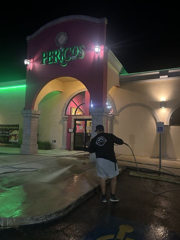 Pressure washing the entrance of a restaurant at night