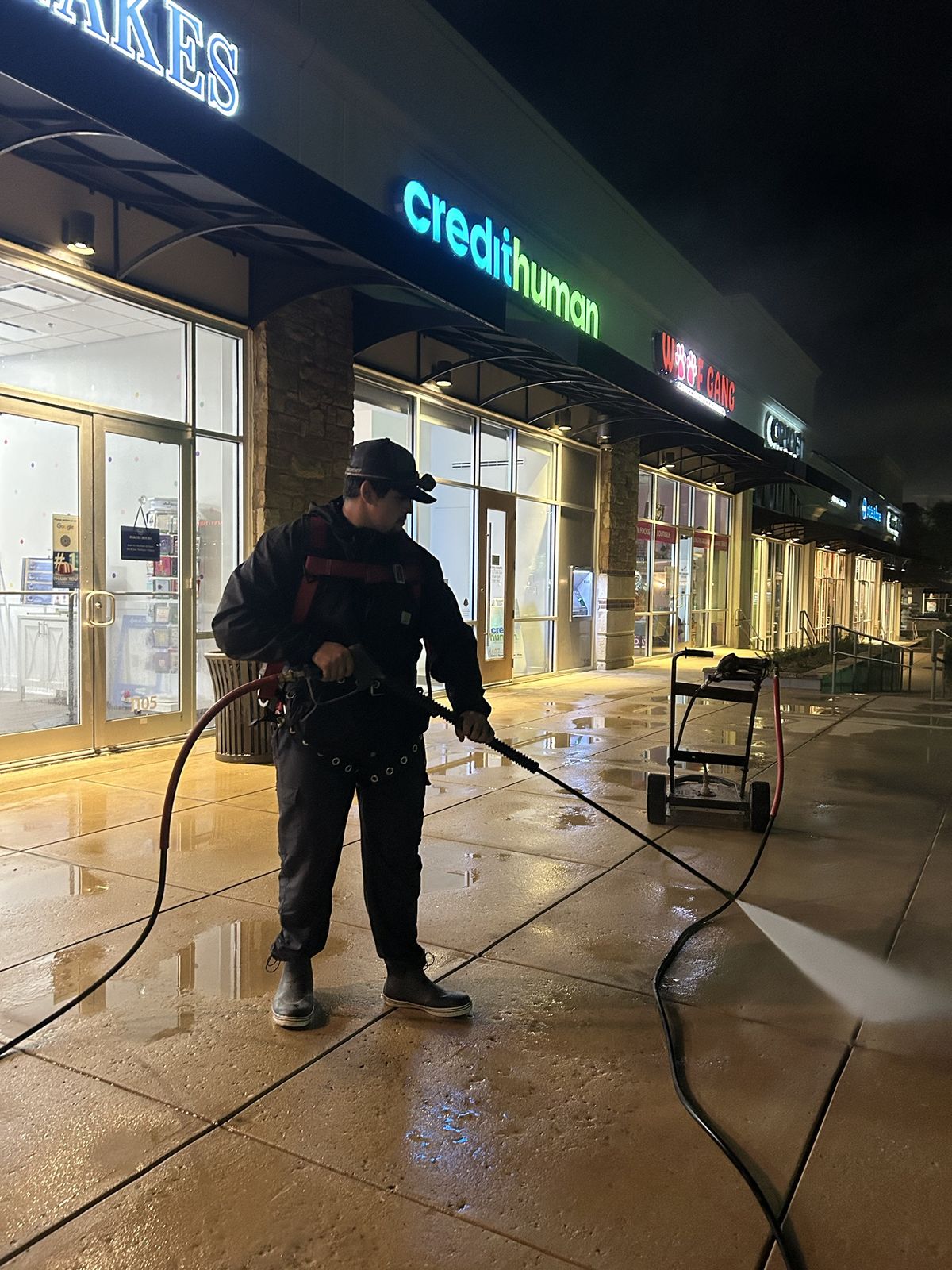 Pressure washing the sidewalk in front of a San Antonio shopping center at night